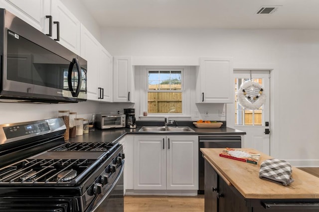 212 Haralson Ave NE, Atlanta, GA 30307 - kitchen with gas stove, a sink, white cabinetry, dishwasher, and light wood-style flooring