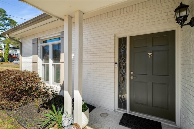 property entrance featuring covered porch and brick siding