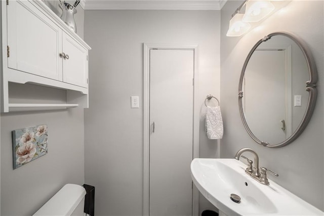 bathroom with a sink, toilet, and crown molding