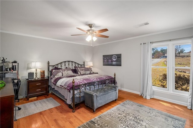 bedroom with visible vents, baseboards, ornamental molding, light wood-style flooring, and a ceiling fan