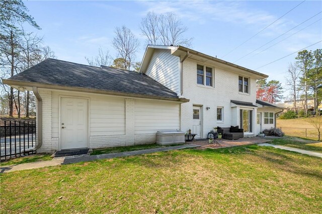 back of property with a patio area, brick siding, a lawn, and fence