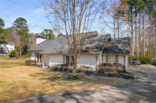 view of front of house featuring brick siding, a chimney, a front lawn, and roof with shingles