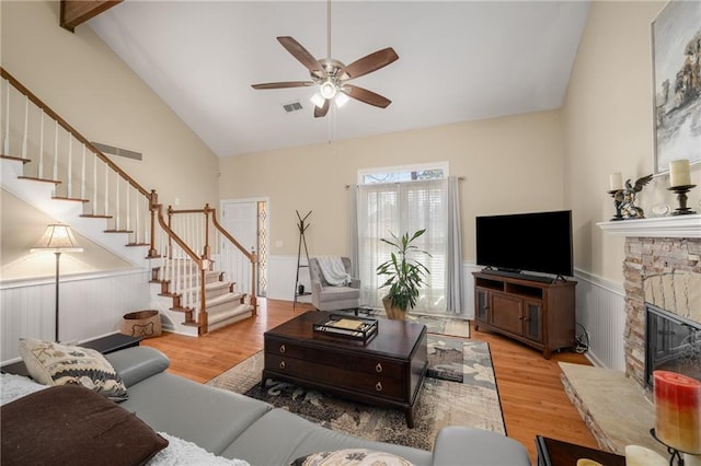 living area with stairs, wood finished floors, visible vents, and a wainscoted wall