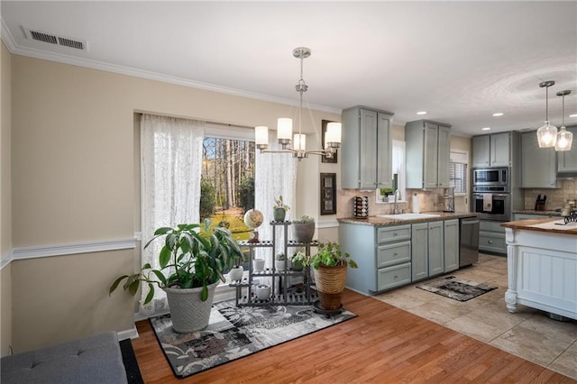 kitchen featuring visible vents, gray cabinets, a sink, appliances with stainless steel finishes, and backsplash