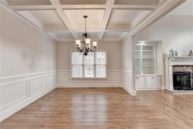 1054 Morgan Garner Dr SW, Lilburn, GA 30047 - unfurnished dining area featuring light wood-type flooring, a chandelier, beam ceiling, coffered ceiling, and a stone fireplace
