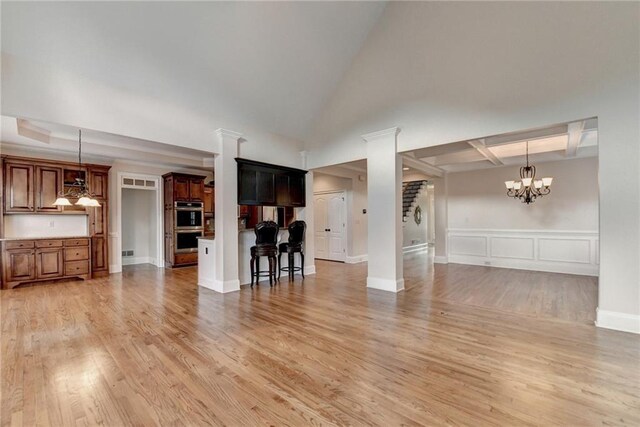 1054 Morgan Garner Dr SW, Lilburn, GA 30047 - unfurnished living room with light wood finished floors, a chandelier, a decorative wall, and a wainscoted wall