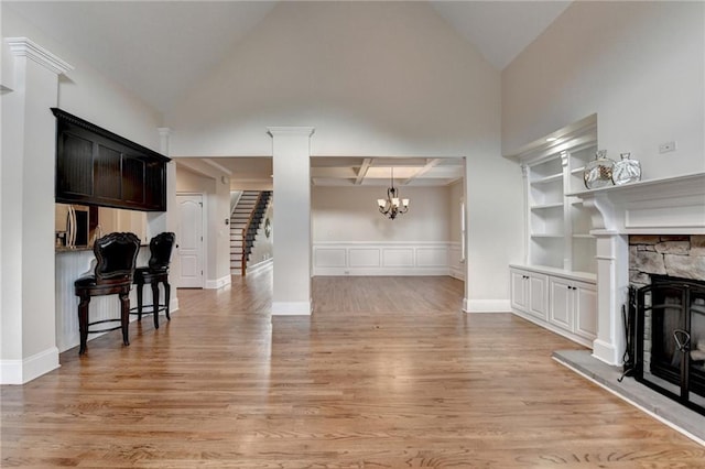 1054 Morgan Garner Dr SW, Lilburn, GA 30047 - living area featuring a chandelier, light wood-type flooring, a stone fireplace, stairs, and a wainscoted wall