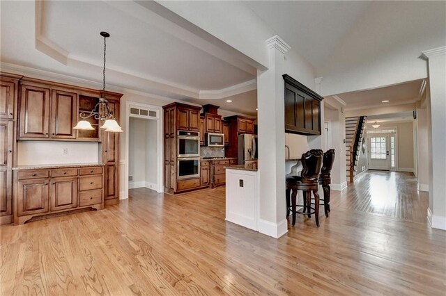 1054 Morgan Garner Dr SW, Lilburn, GA 30047 - kitchen with stainless steel appliances, crown molding, light wood-type flooring, hanging light fixtures, and a kitchen breakfast bar