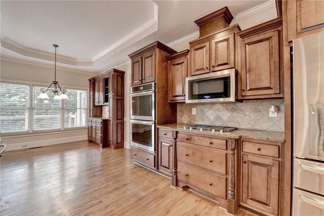 1054 Morgan Garner Dr SW, Lilburn, GA 30047 - kitchen with stainless steel appliances, ornamental molding, decorative backsplash, light wood-style flooring, and a tray ceiling
