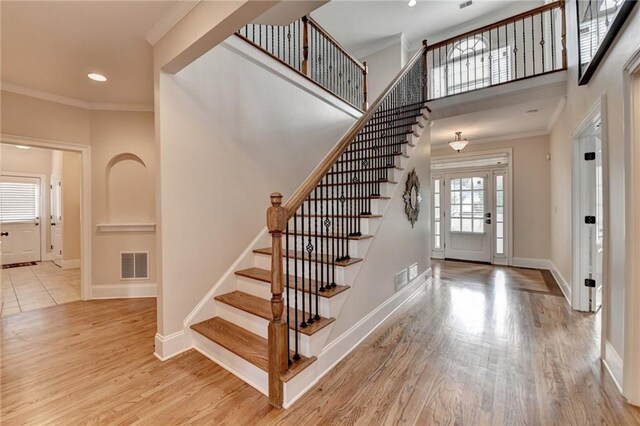 1054 Morgan Garner Dr SW, Lilburn, GA 30047 - staircase featuring baseboards, wood finished floors, crown molding, recessed lighting, and a towering ceiling
