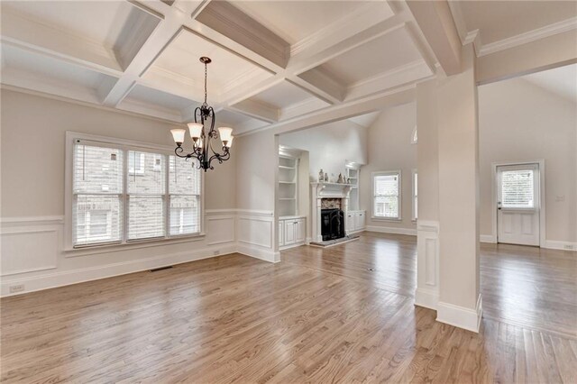 1054 Morgan Garner Dr SW, Lilburn, GA 30047 - unfurnished living room featuring light wood-type flooring, a chandelier, beamed ceiling, a fireplace with raised hearth, and a wainscoted wall