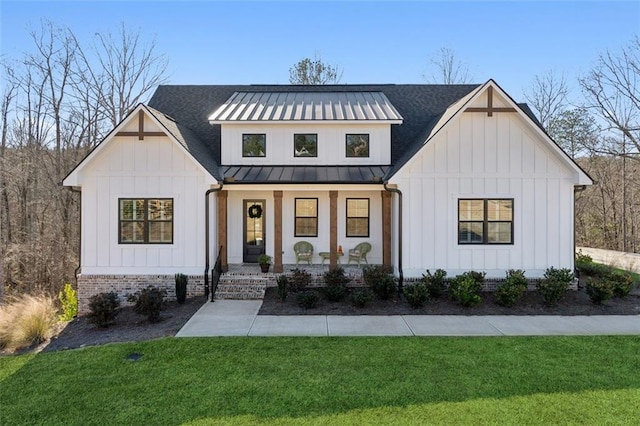 modern farmhouse with brick siding, board and batten siding, a front yard, covered porch, and a standing seam roof