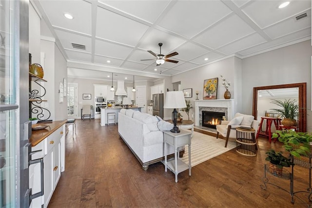 living room with visible vents, coffered ceiling, a lit fireplace, and dark wood-style flooring