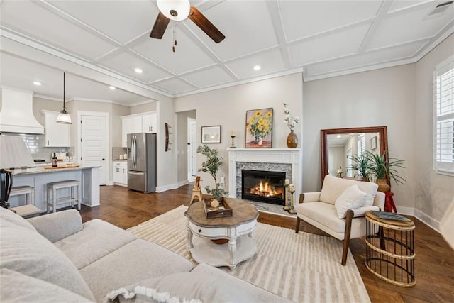 living area featuring visible vents, baseboards, coffered ceiling, and a stone fireplace