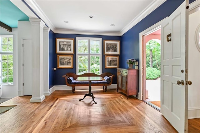 living area featuring decorative columns, baseboards, and crown molding