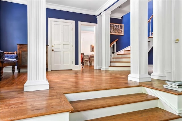 foyer featuring stairway, wood finished floors, baseboards, ornate columns, and crown molding