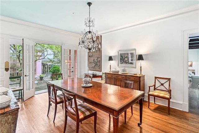 dining area featuring an inviting chandelier, light wood-style flooring, french doors, and ornamental molding