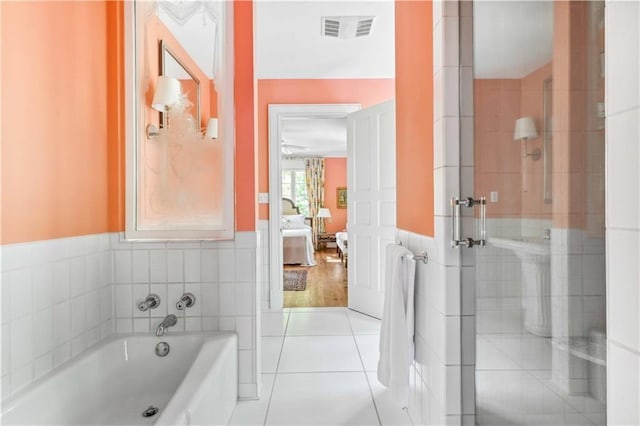 full bathroom featuring visible vents, tile walls, wainscoting, tile patterned flooring, and a bath