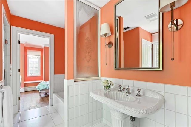 bathroom featuring a tub to relax in, a wainscoted wall, visible vents, tile patterned flooring, and tile walls