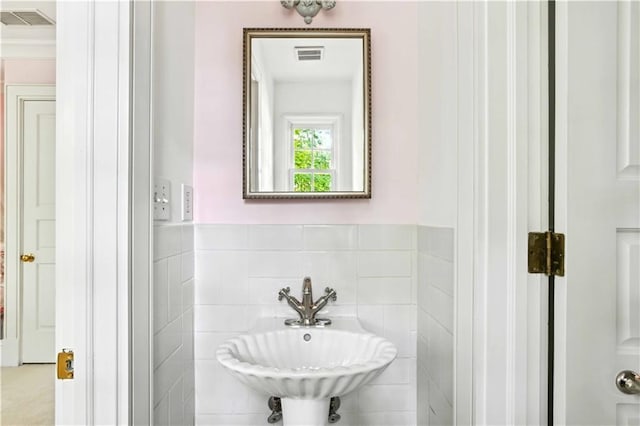 bathroom featuring tile walls, visible vents, and a sink