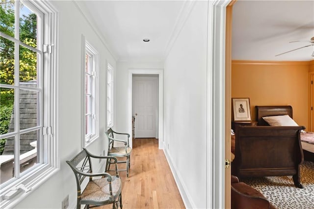 hall featuring a wealth of natural light, baseboards, light wood-style floors, and ornamental molding