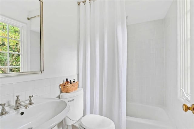 bathroom with tasteful backsplash, toilet, shower / tub combo with curtain, tile walls, and a sink