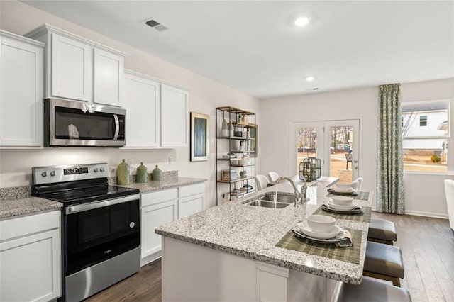 314 Sound Cir, Stockbridge, GA 30281 - kitchen featuring appliances with stainless steel finishes, a sink, dark wood-style flooring, a kitchen breakfast bar, and white cabinets