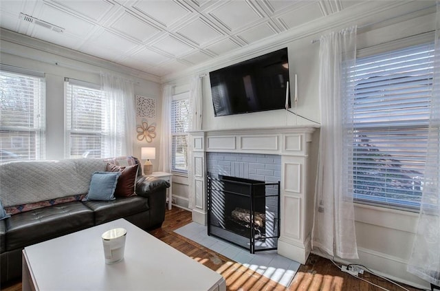 living room with a fireplace, wood finished floors, visible vents, an ornate ceiling, and crown molding