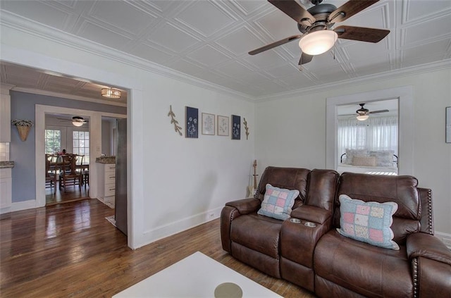 living area featuring crown molding, wood finished floors, an ornate ceiling, and baseboards