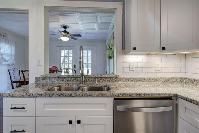 kitchen featuring a sink, stainless steel dishwasher, backsplash, light stone countertops, and an ornate ceiling