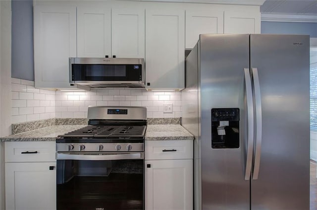 kitchen with appliances with stainless steel finishes, white cabinets, light stone counters, and decorative backsplash