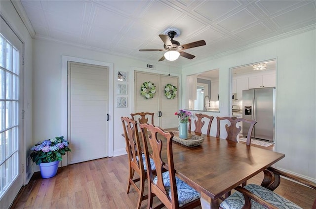 dining area featuring light wood-style floors, ornamental molding, baseboards, and a ceiling fan