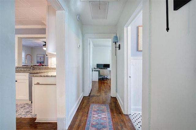 hall with baseboards, attic access, ornamental molding, and dark wood-style flooring