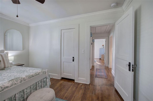 bedroom featuring dark wood-style flooring, crown molding, attic access, a ceiling fan, and baseboards