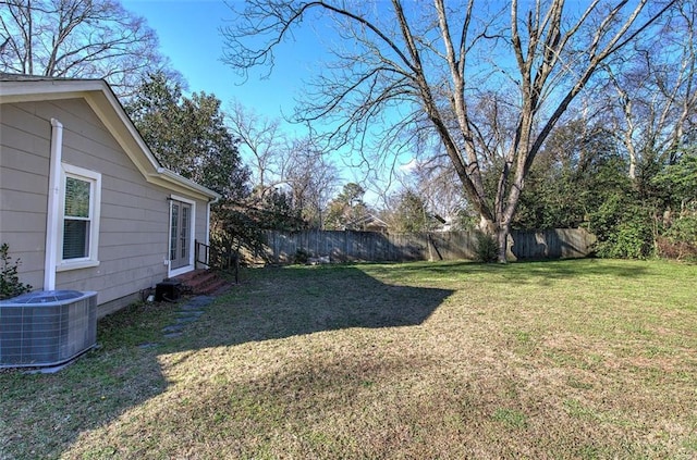 view of yard with entry steps, central AC unit, and fence private yard