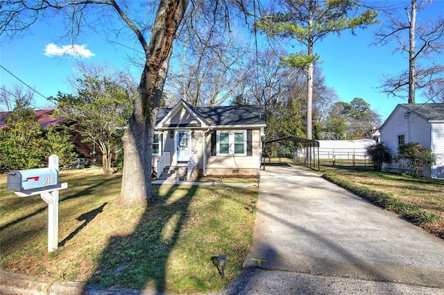 bungalow featuring driveway, a detached carport, fence, and a front yard