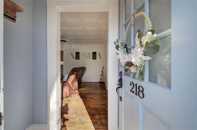 hall featuring an ornate ceiling, ornamental molding, baseboards, and wood finished floors