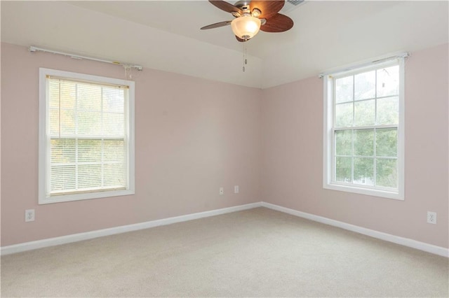 carpeted empty room with a wealth of natural light and ceiling fan