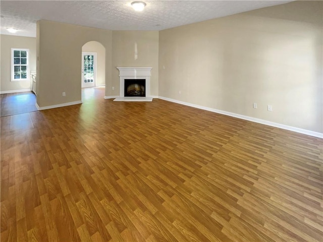 20 Pine Canyon Dr SW Unit 24, Atlanta, GA 30331 - unfurnished living room featuring a fireplace with raised hearth, baseboards, arched walkways, and wood finished floors