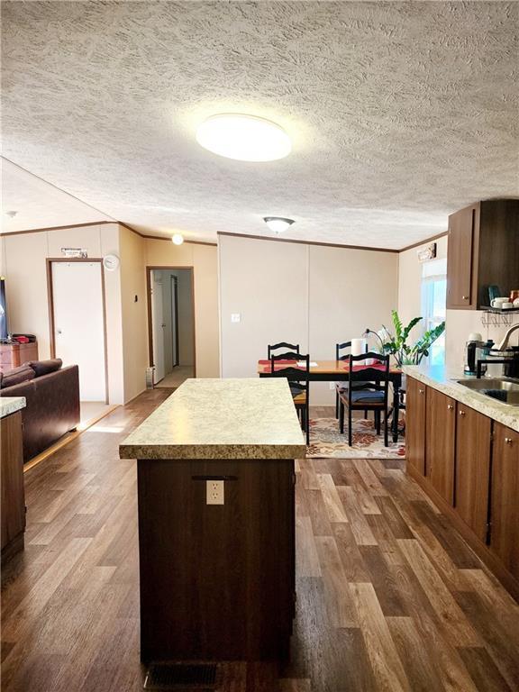 kitchen featuring dark hardwood / wood-style flooring, sink, a kitchen island, and a textured ceiling