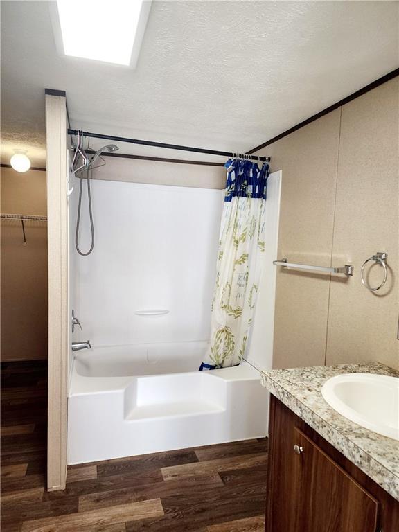 bathroom with wood-type flooring, vanity, shower / bath combo with shower curtain, and a textured ceiling