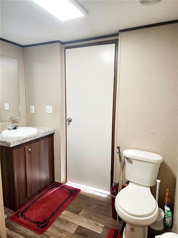 bathroom with vanity, toilet, and hardwood / wood-style floors