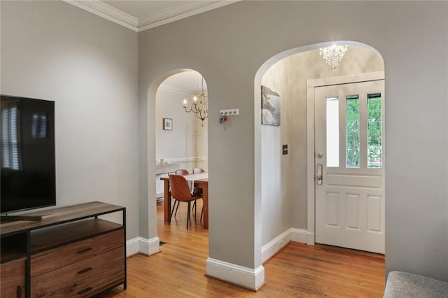 entrance foyer featuring crown molding, light hardwood / wood-style flooring, and an inviting chandelier