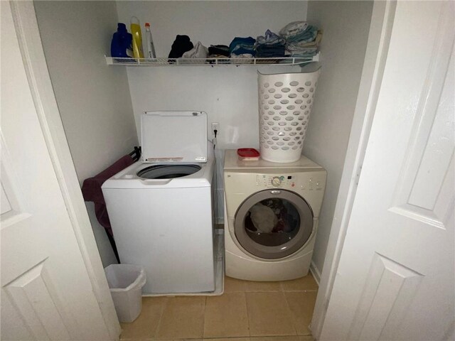 clothes washing area with washer and dryer and light tile patterned floors