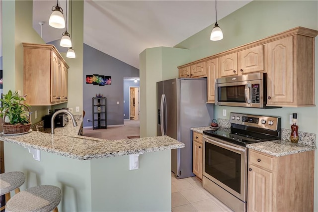 kitchen featuring lofted ceiling, light brown cabinets, a peninsula, a kitchen breakfast bar, and appliances with stainless steel finishes