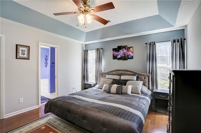 bedroom featuring a tray ceiling, multiple windows, and wood finished floors