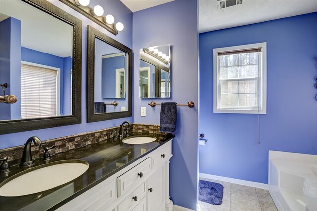 bathroom featuring tile patterned floors, a sink, visible vents, and baseboards