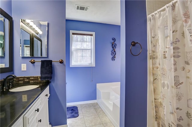 bathroom featuring tile patterned flooring, vanity, visible vents, baseboards, and a bath