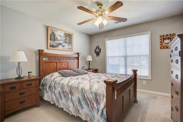 bedroom featuring a ceiling fan, light carpet, a textured ceiling, and baseboards