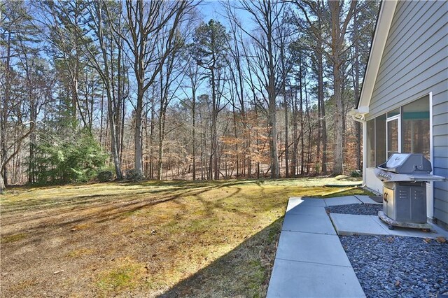 view of yard with a sunroom and a view of trees